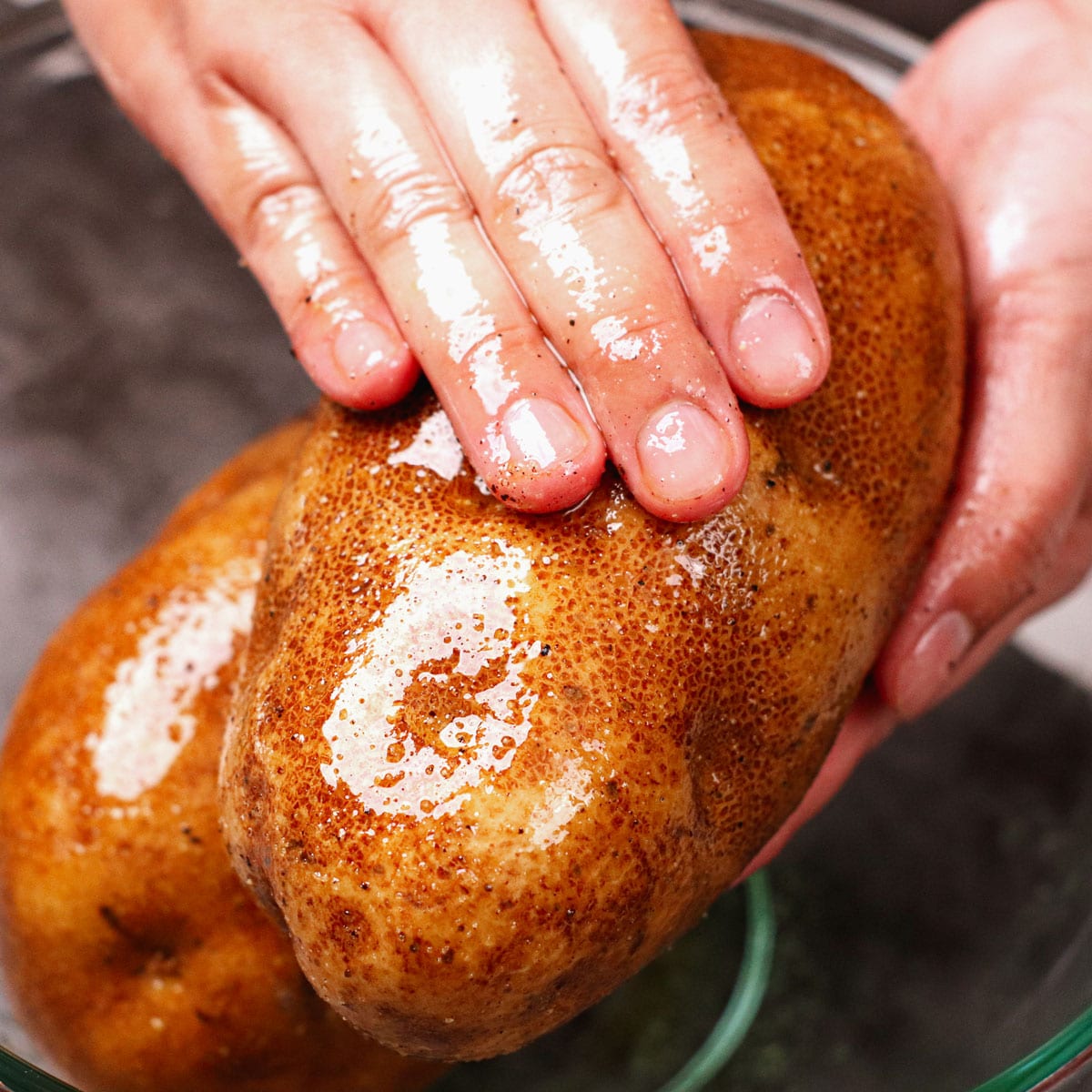 Seasoning whole potato with olive oil, salt and pepper
