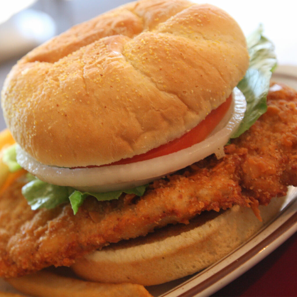 air fried breaded pork tenderloin, served as a sandwich with fries on the side