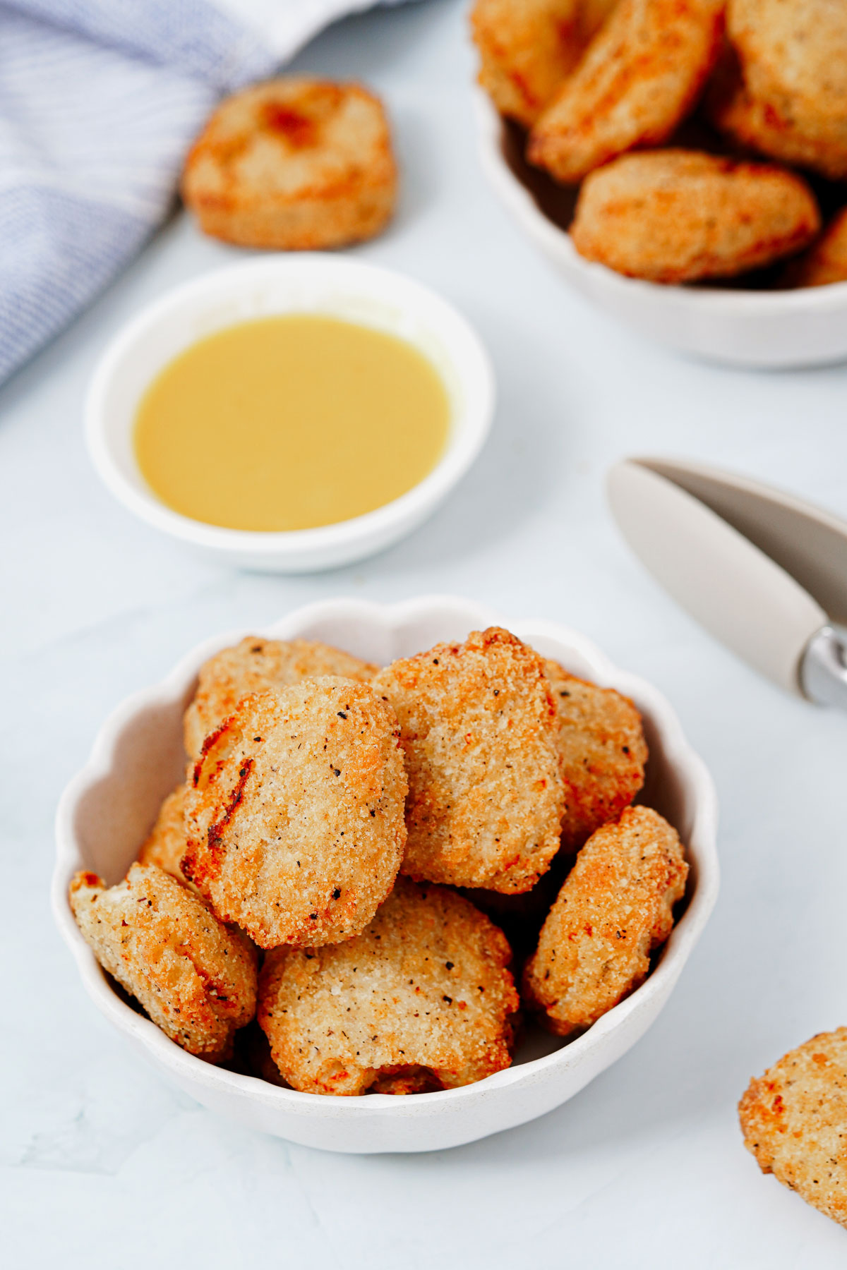 Air fryer frozen chicken nuggets recipe bite shot, served in a small bowl with honey mustard dipping sauce