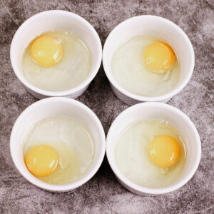 Cracked eggs in ramekin bowls