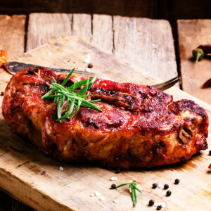 air fried pork shoulder steak, served on a board with rosemary garnish