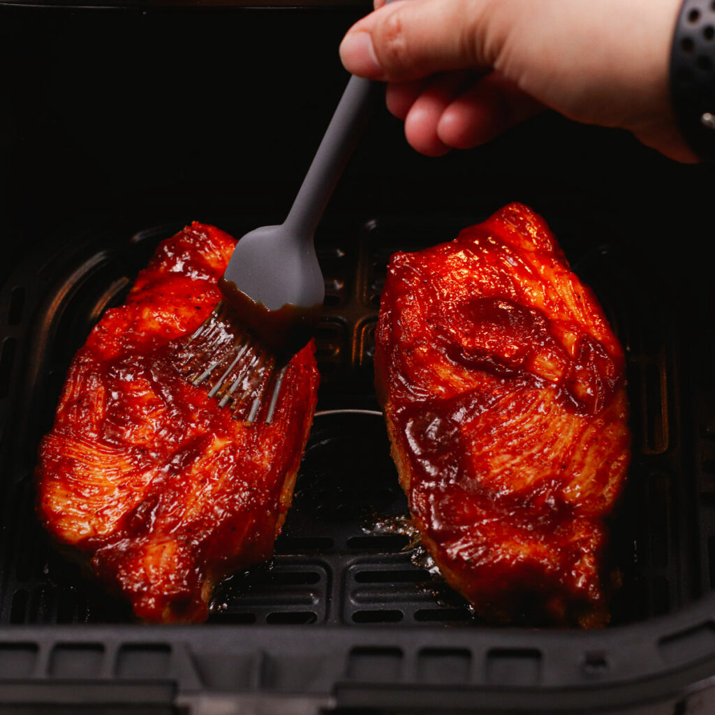 Basting pork chops with BBQ sauce.
