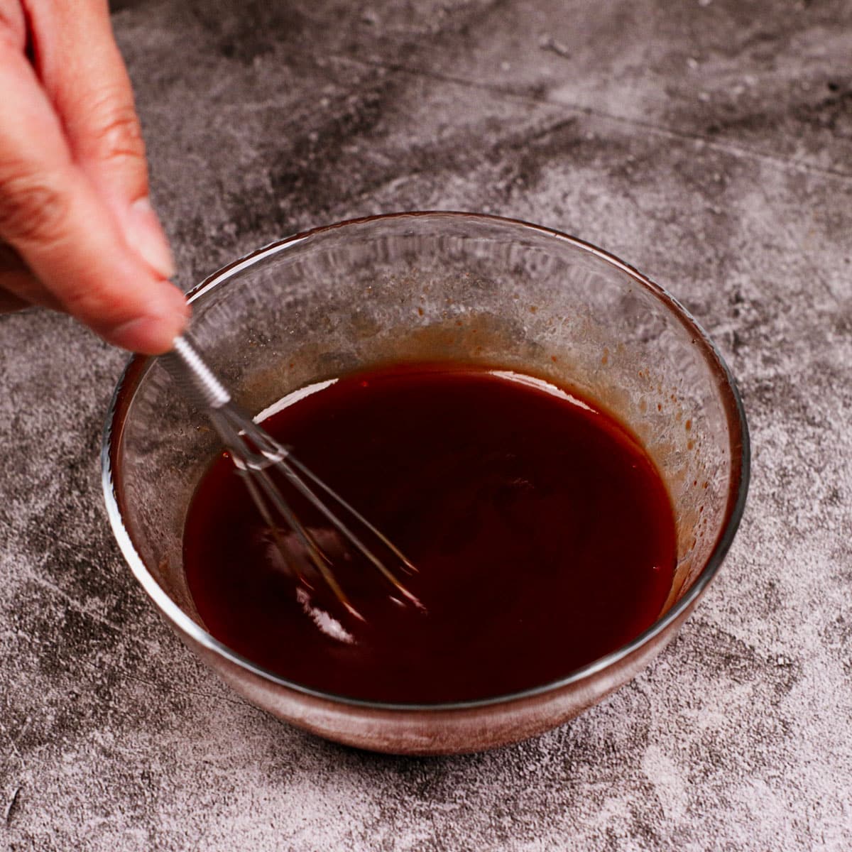 Mixing barbecue sauce in a small glass bowl.