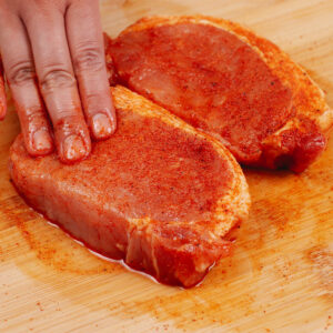 Seasoning pork chops with dry rub mixture.